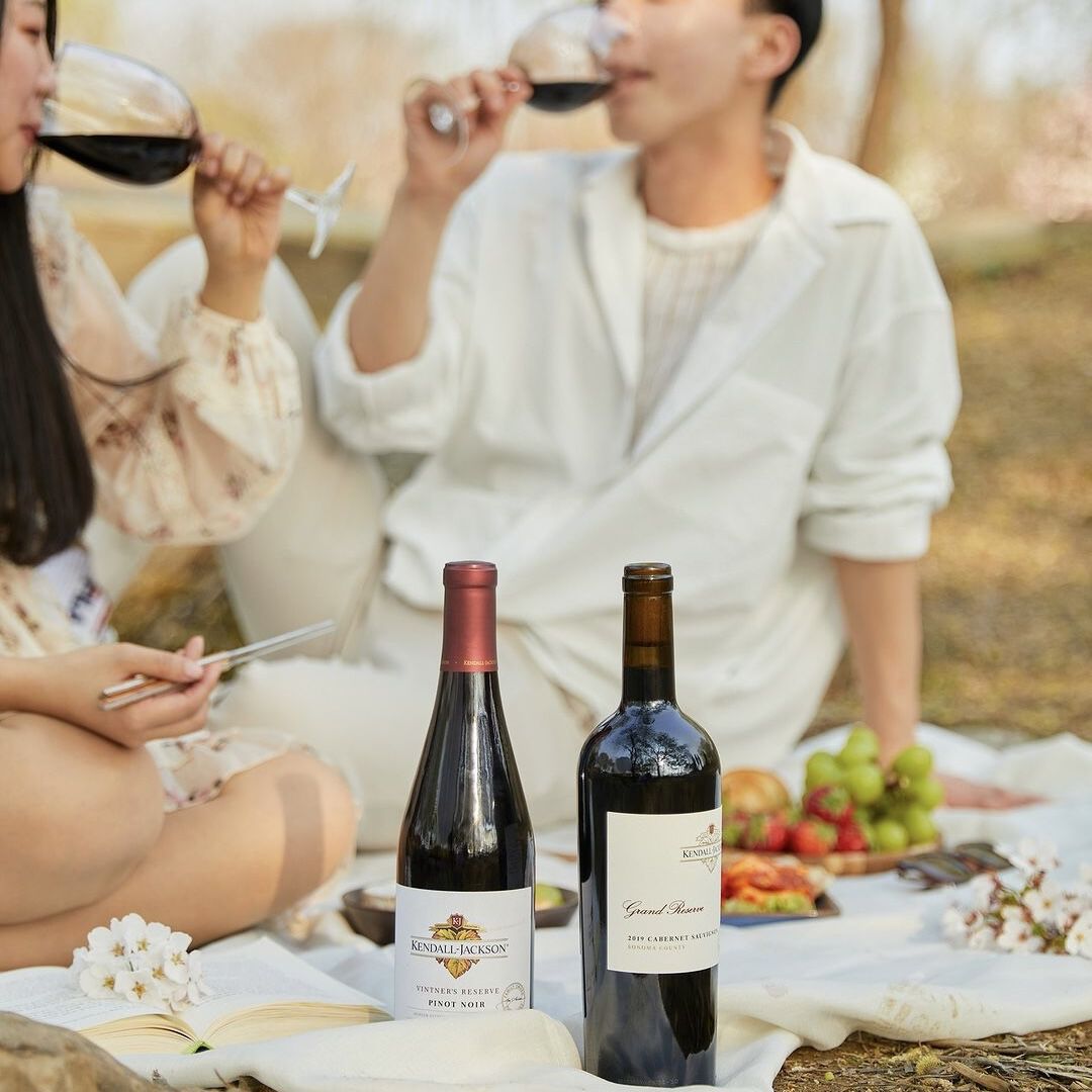 @kjwines.kr Instagram spotlight - bottles of red wines with a picnic in a park in South Korea